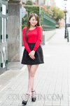 真っ赤なロングスリーブシャツと黒のミニスカートを履いている女性のプロフィール写真（全身カット）
